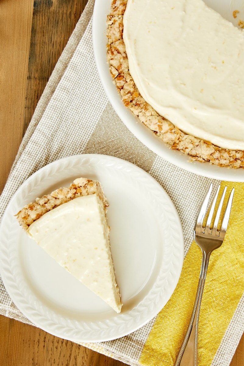 overhead view of a slice of Lemon Icebox Pie on a white plate with the remaining pie beside it