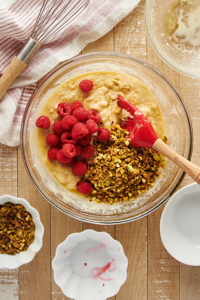overhead view of muffin batter with raspberries and pistachios added