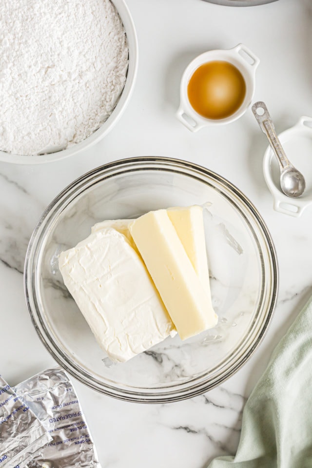 Overhead view of cream cheese and butter sticks in glass mixing bowl