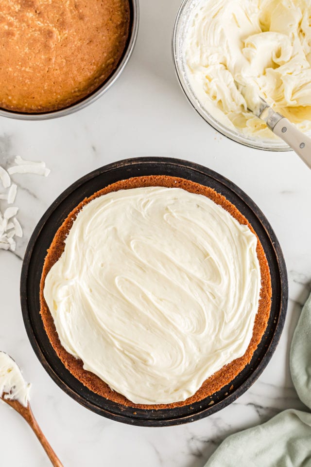 Overhead view showing first layer of coconut cake with frosting on top