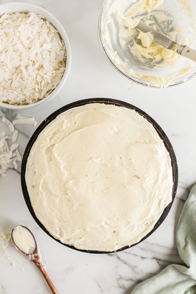 Overhead view of frosted coconut cake before adding coconut flakes