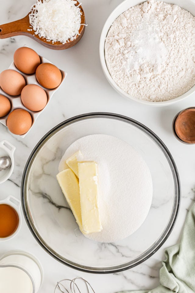 Sticks of butter and sugar in glass mixing bowl