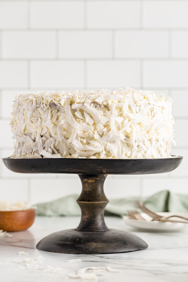 Side view of whole coconut cake on cake stand