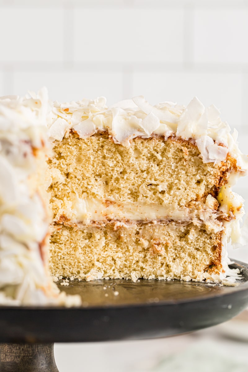 View of cut coconut cake on cake stand, showing layers