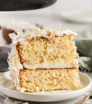 Slice of coconut cake standing upright on plate