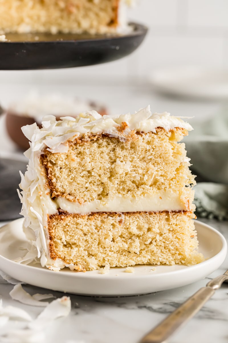 Slice of coconut cake standing upright on plate