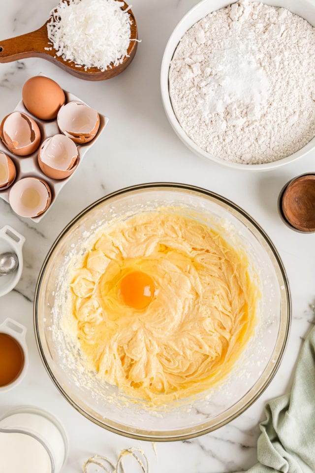 Overhead view of egg cracked into cake batter bowl