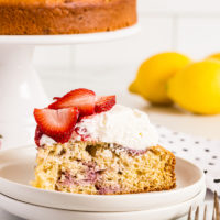 Lemon-Strawberry Shortcake on plate with remaining cake and lemons in background