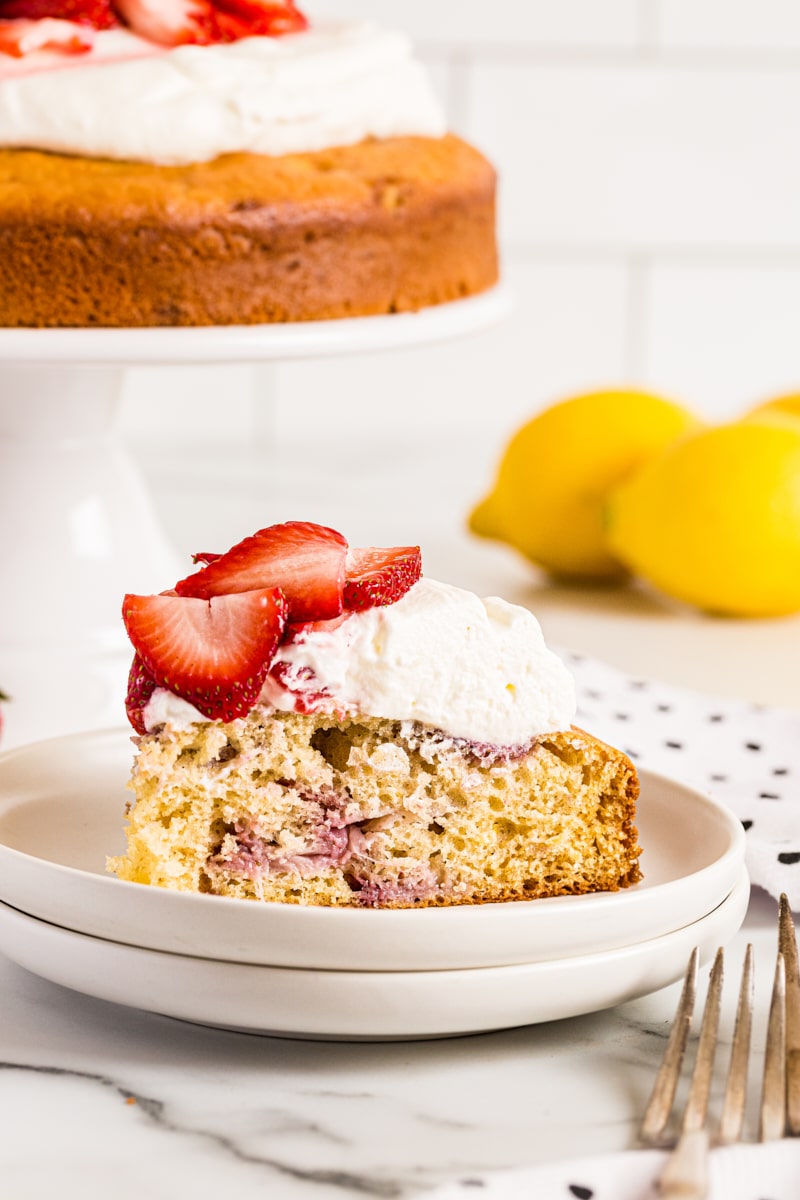 Lemon-Strawberry Shortcake on plate with remaining cake and lemons in background