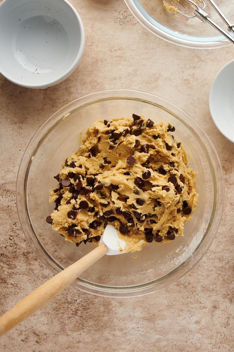 overhead view of mixed Cheesecake-Stuffed Chocolate Chip Cookie dough with chocolate chips stirred into the dough