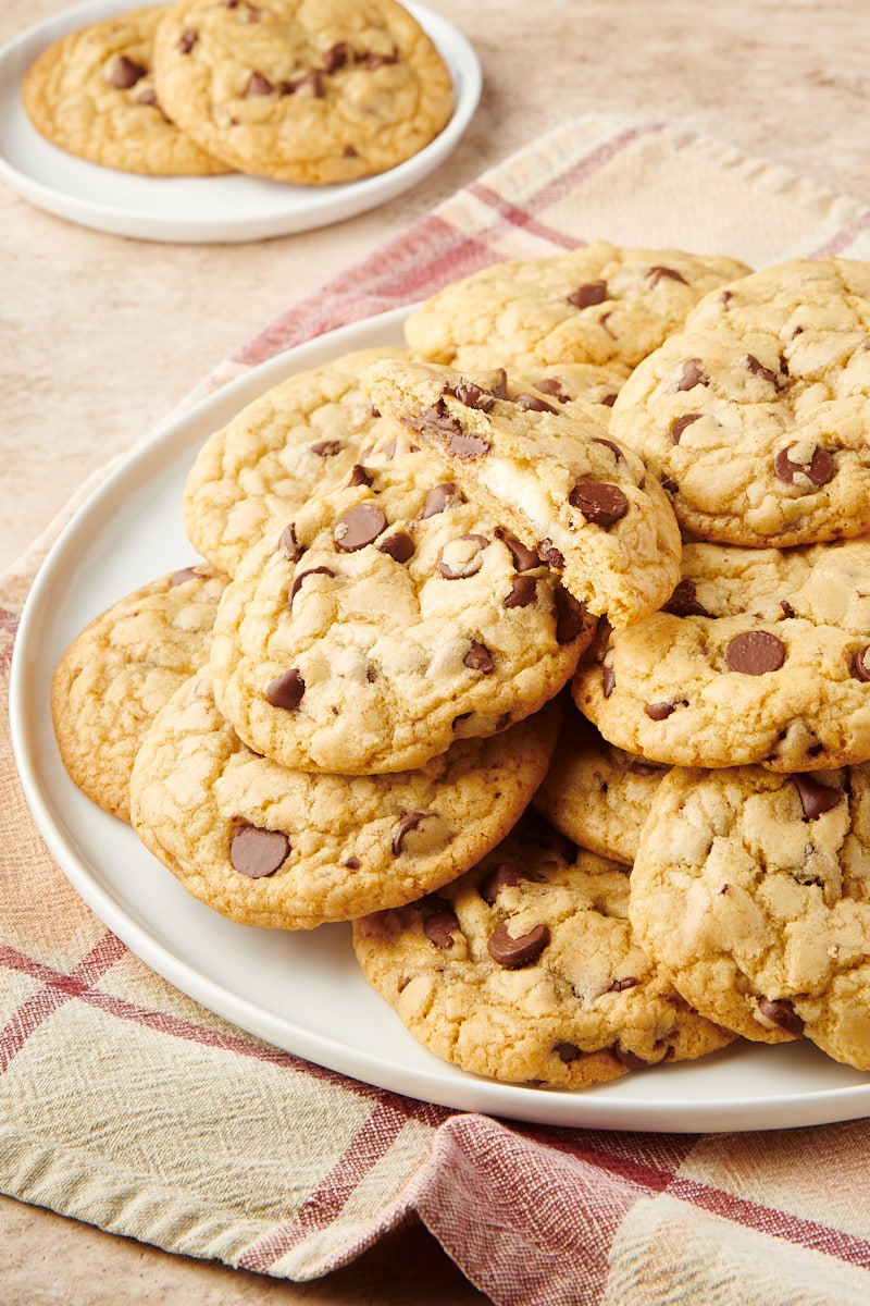 Cheesecake-Stuffed Chocolate Chip Cookies piled on a large white plate