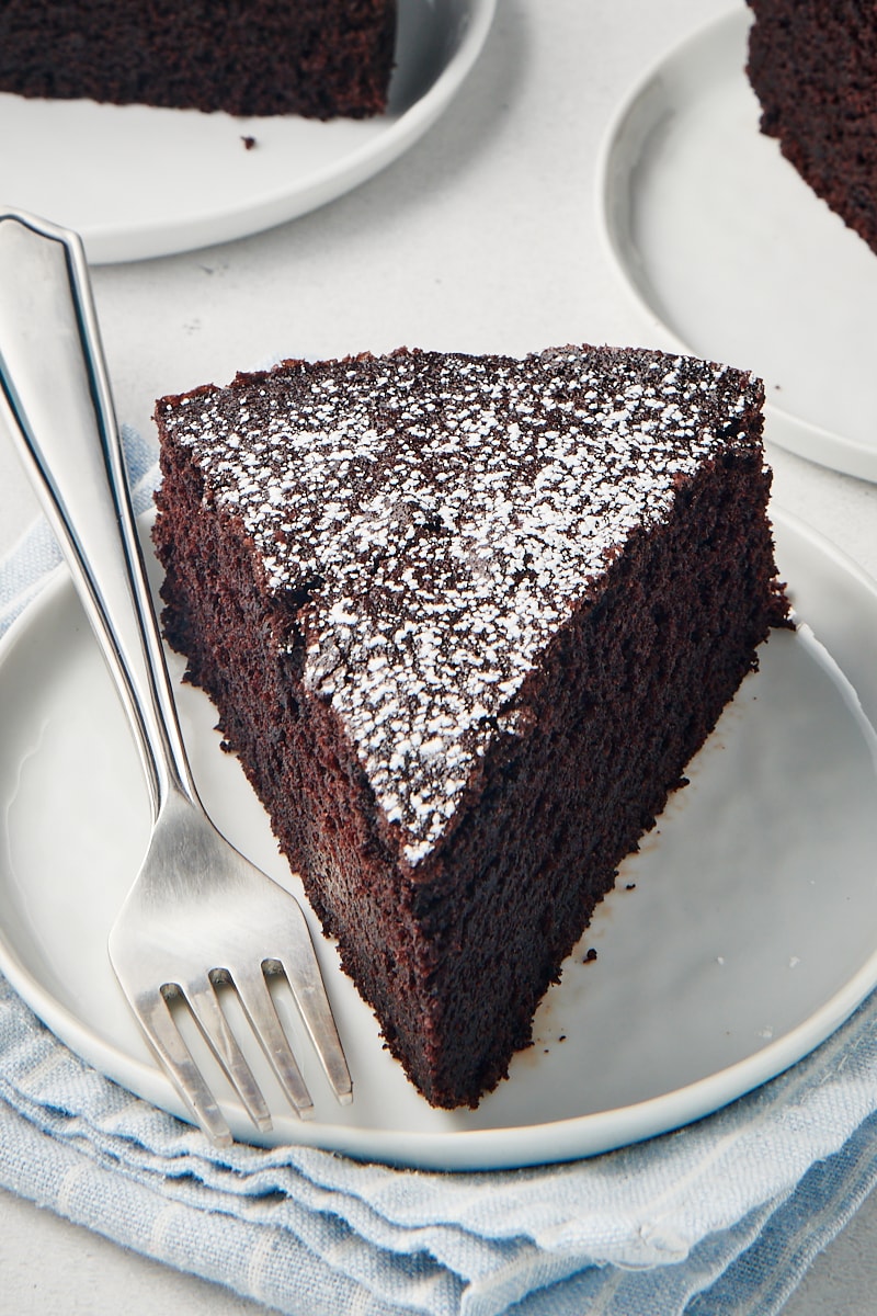 Slice of cocoa cake on white plate with fork