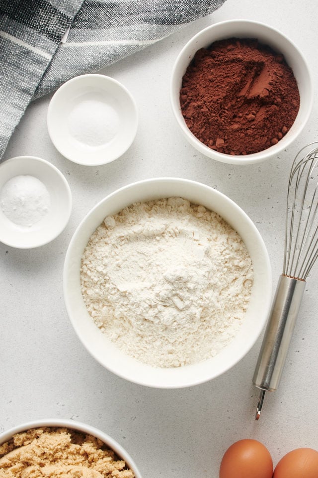 Overhead view of bowls of flour, cocoa powder, and other dry ingredients