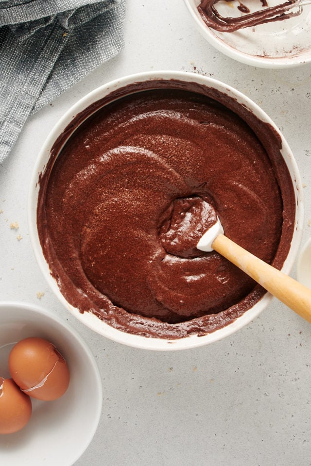 Overhead view of chocolate cake batter in mixing bowl with spatula