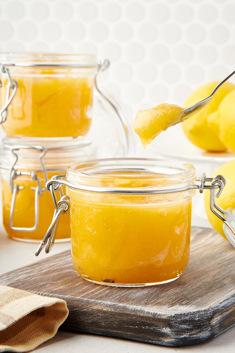 lemon curd in a glass jar with a spoonful above