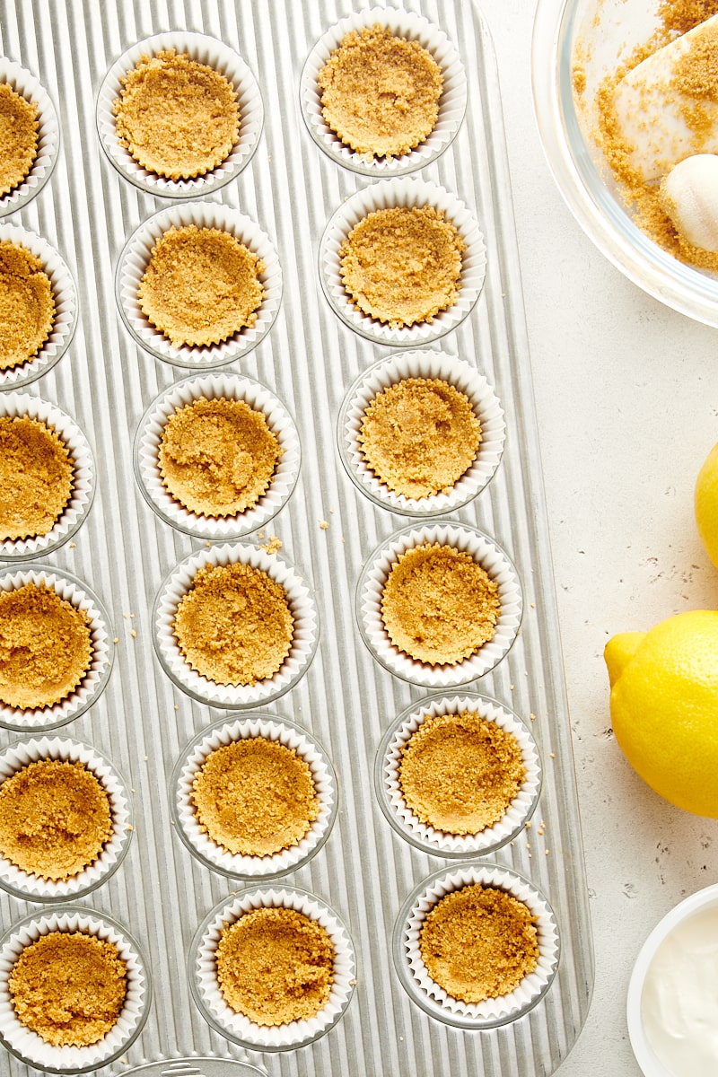 overhead view of graham cracker crust pressed into lined mini muffin cups