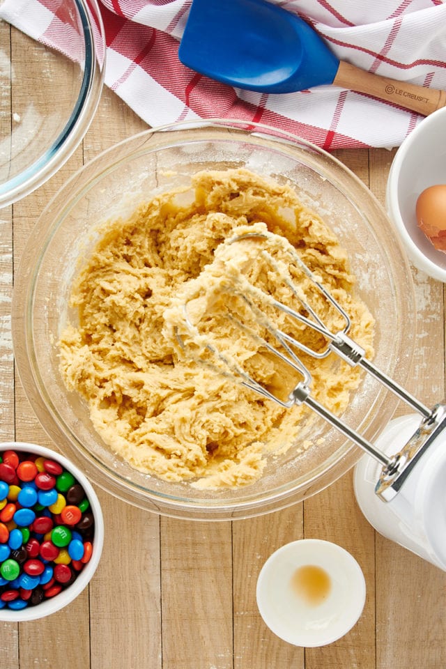 Hand mixer set over bowl of cookie dough after beating it