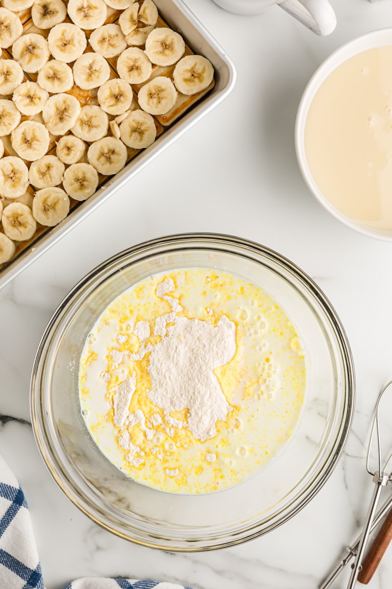 Overhead view of vanilla pudding mix and milk in glass mixing bowl