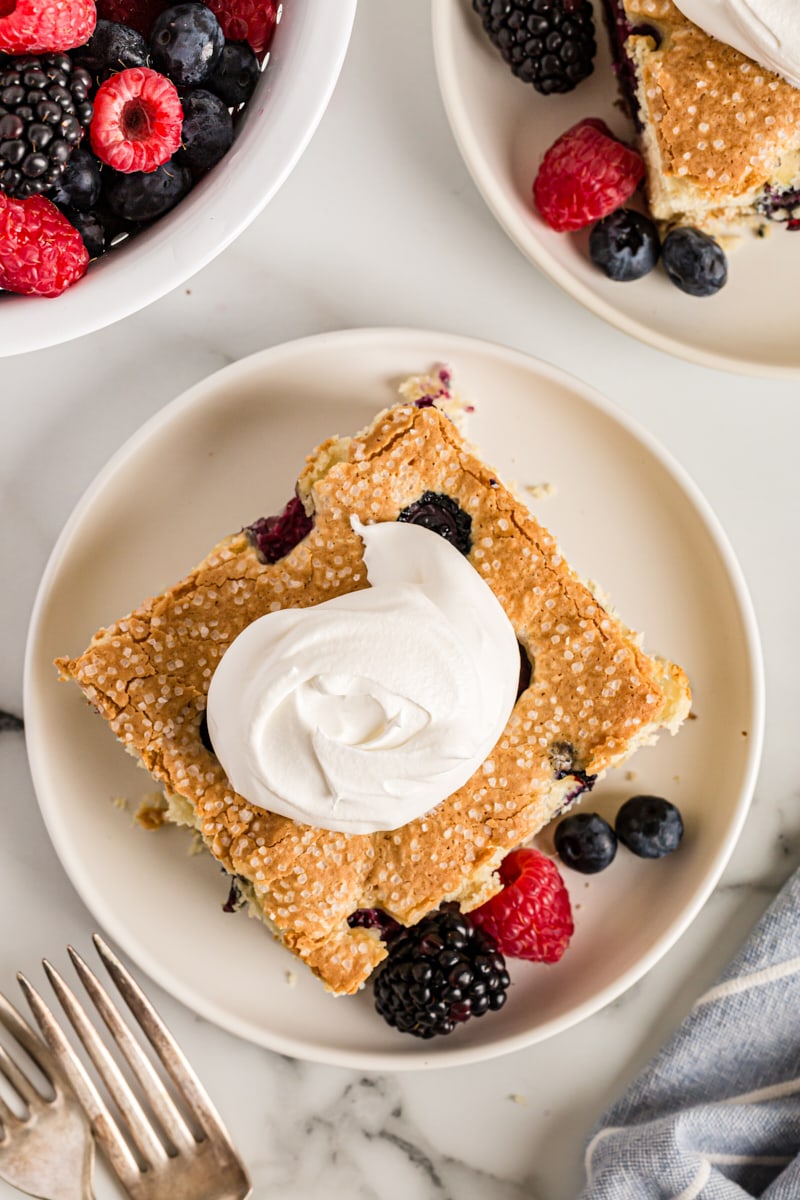 Overhead view of berry vanilla cake on plate with dollop of whipped cream