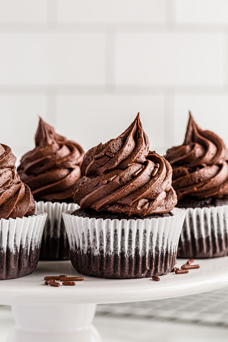 frosted chocolate cupcakes on a white cake stand