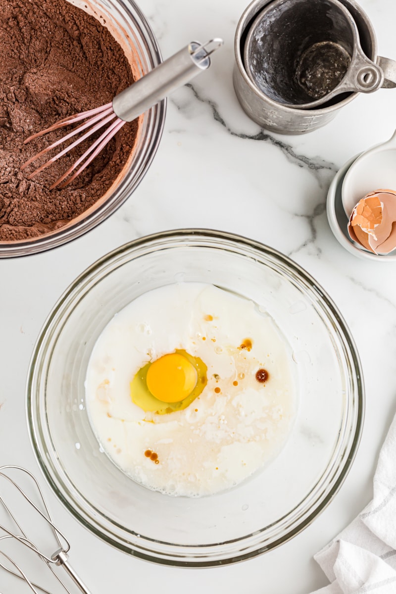 overhead view of buttermilk, oil, egg, vanilla, and water in a glass mixing bowl