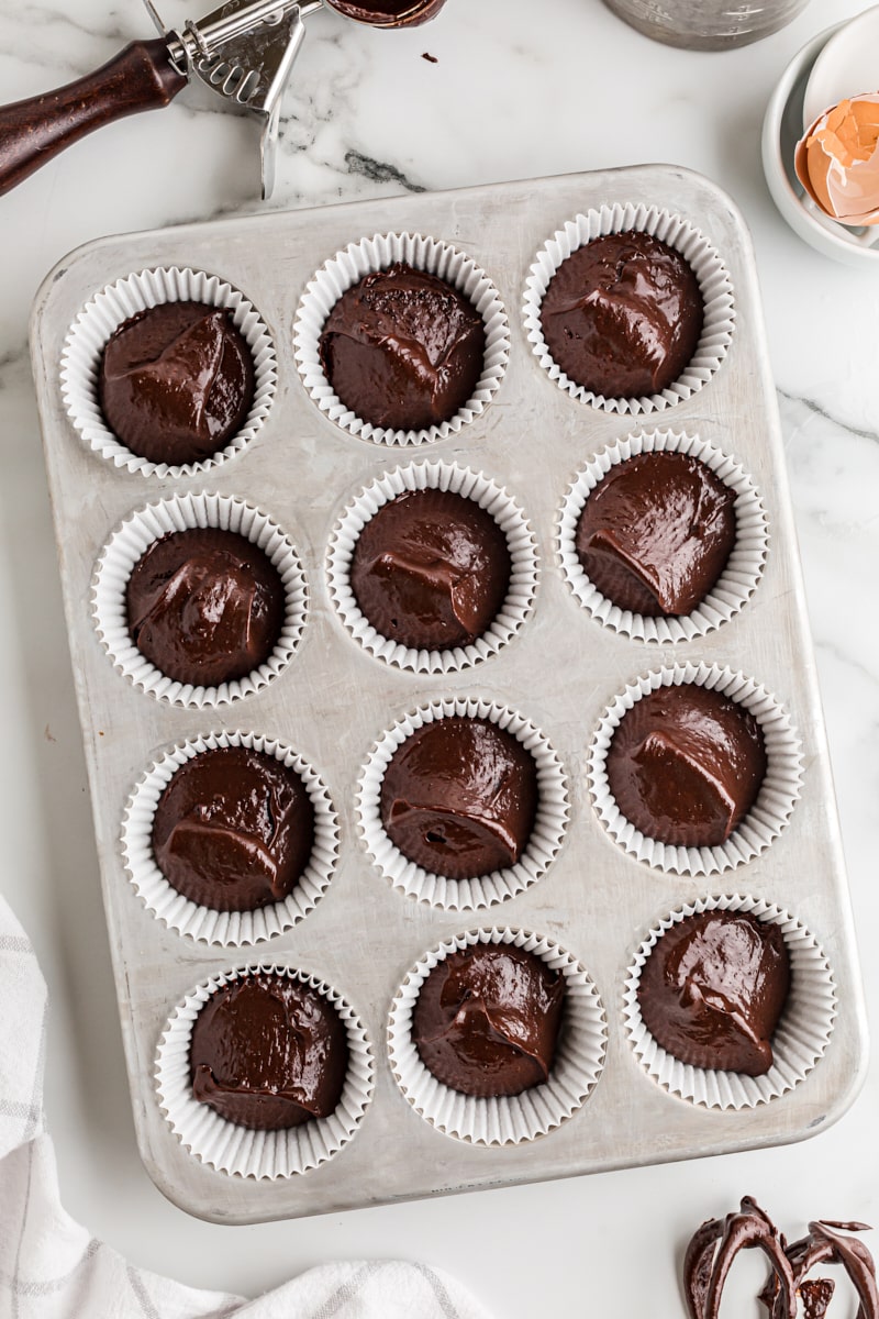 overhead view of unbaked chocolate cupcake batter in a muffin pan