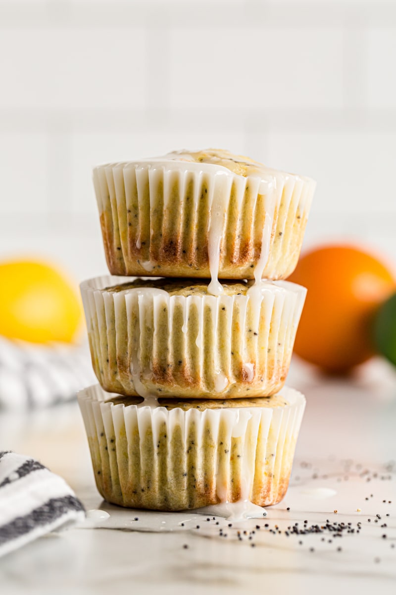 Stack of 3 citrus poppy seed muffins with glaze dripping down sides
