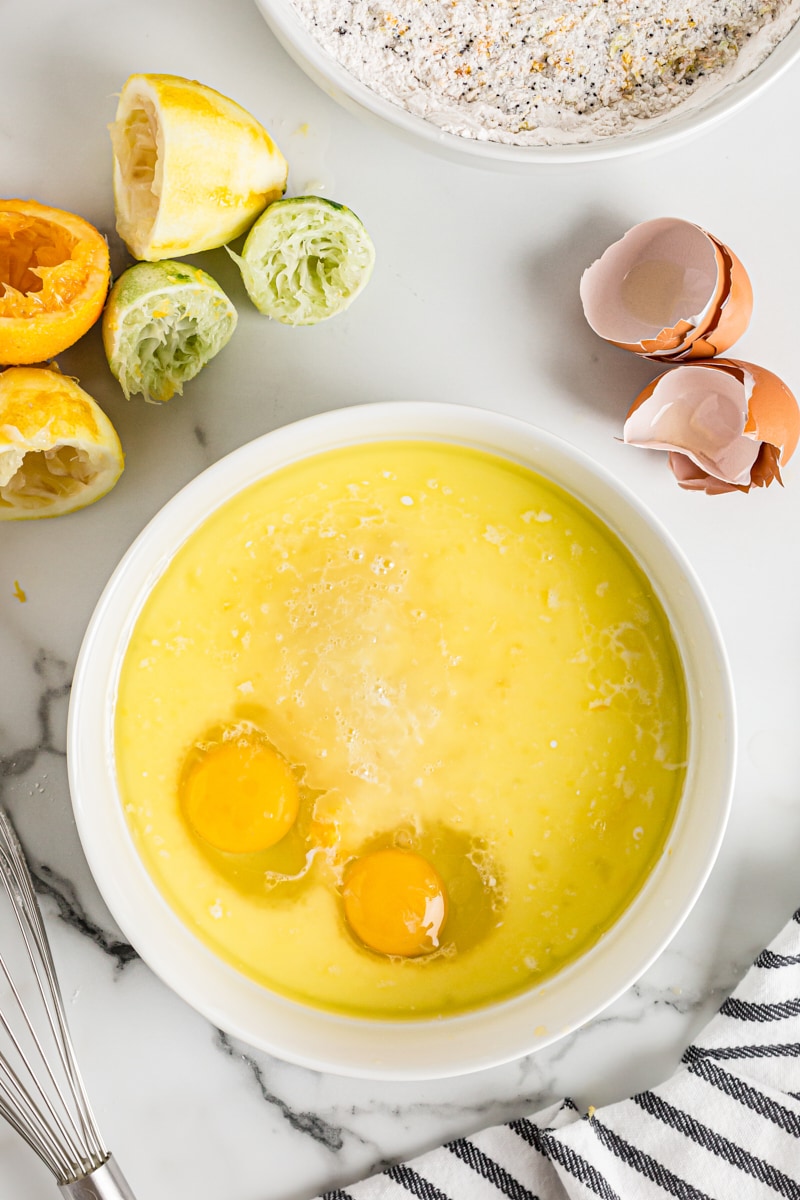 Overhead view of 2 eggs cracked into bowl of wet muffin ingredients