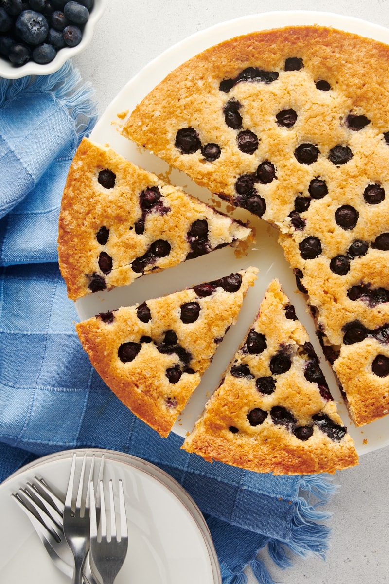 Overhead view of blueberry cake with 3 slices cut