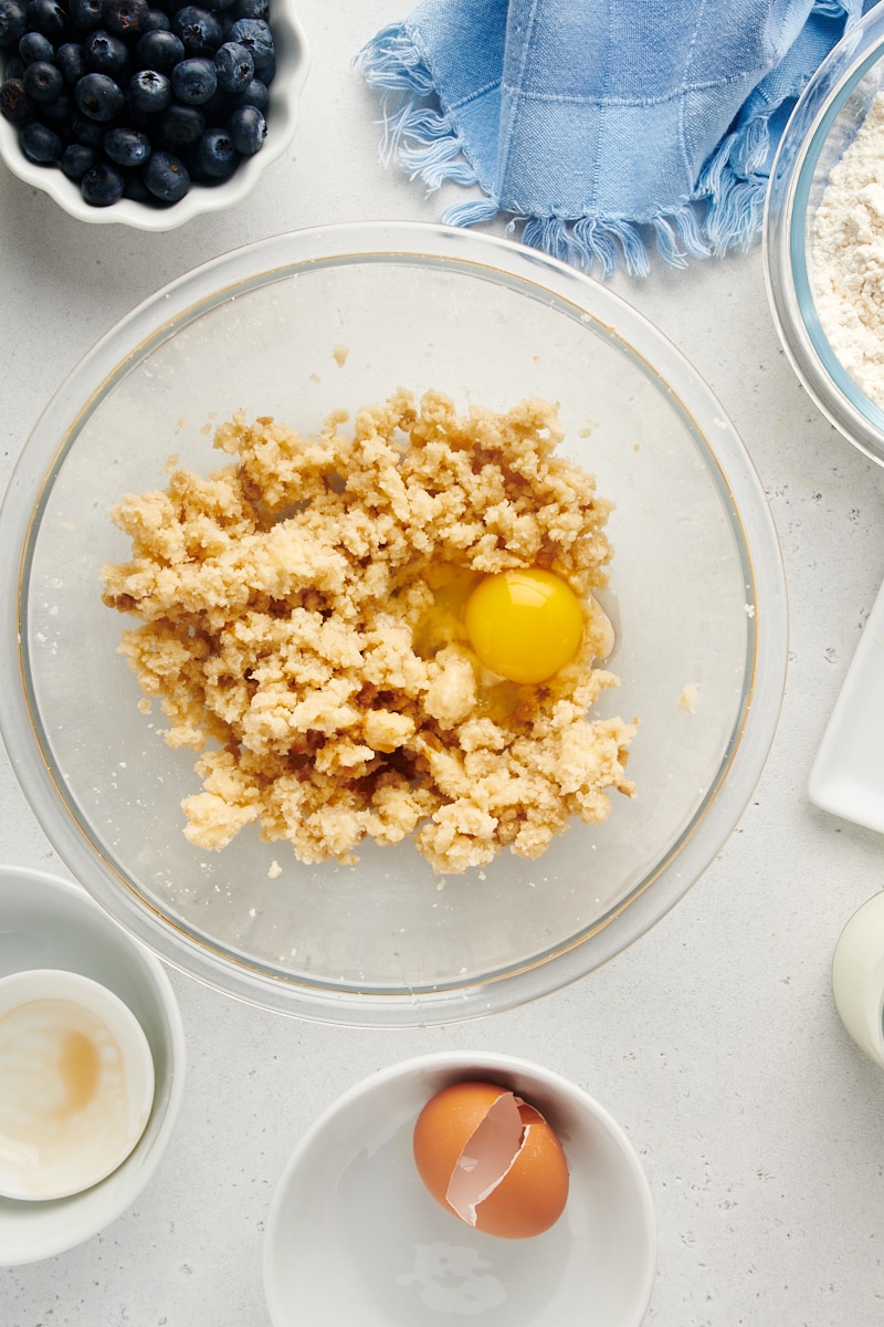 Overhead view of egg in bowl of creamed butter and sugar