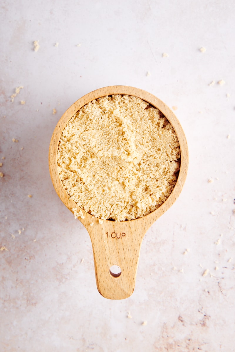 overhead view of light brown sugar in a wooden measuring cup