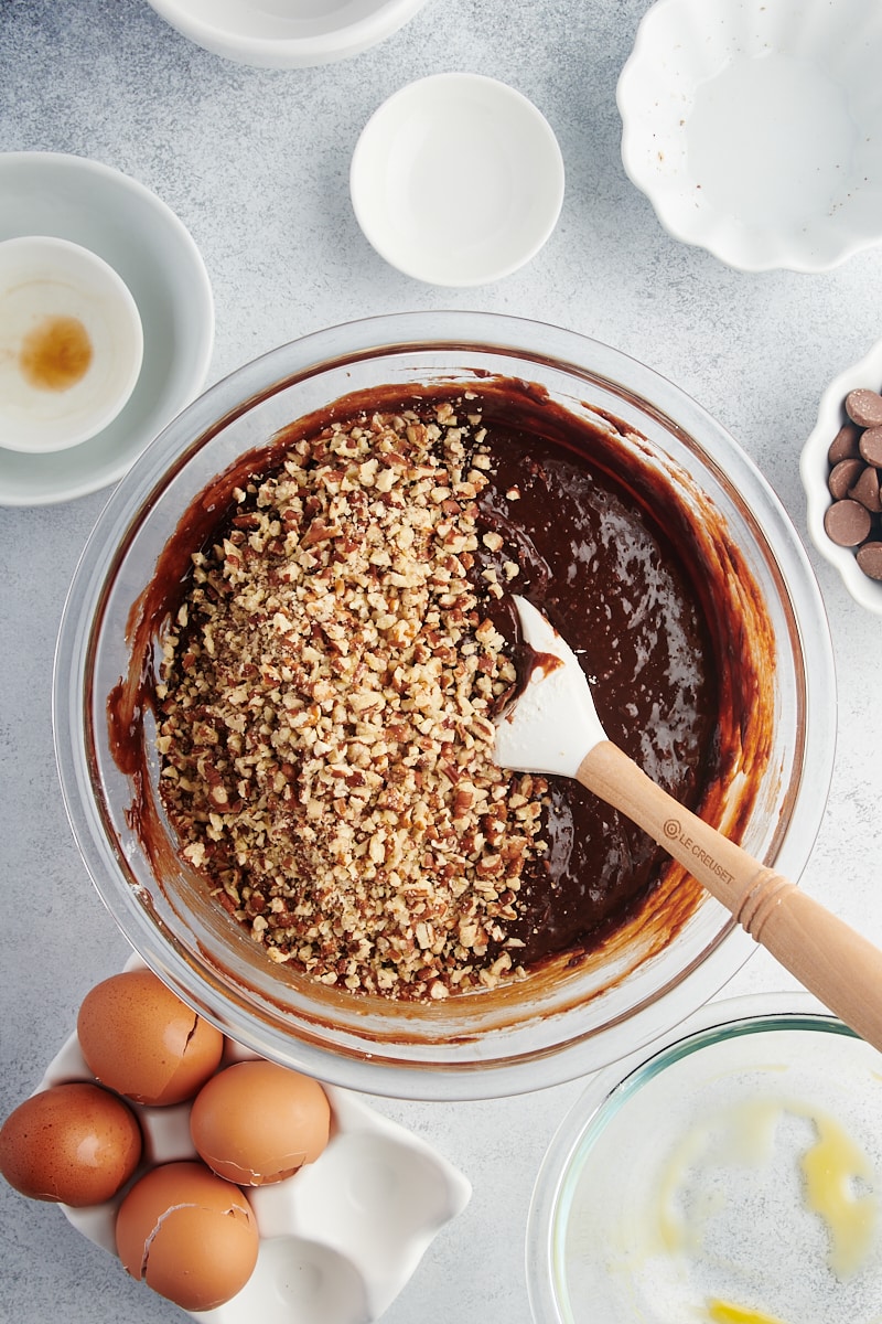 Overhead view of nuts being stirred into brownie batter