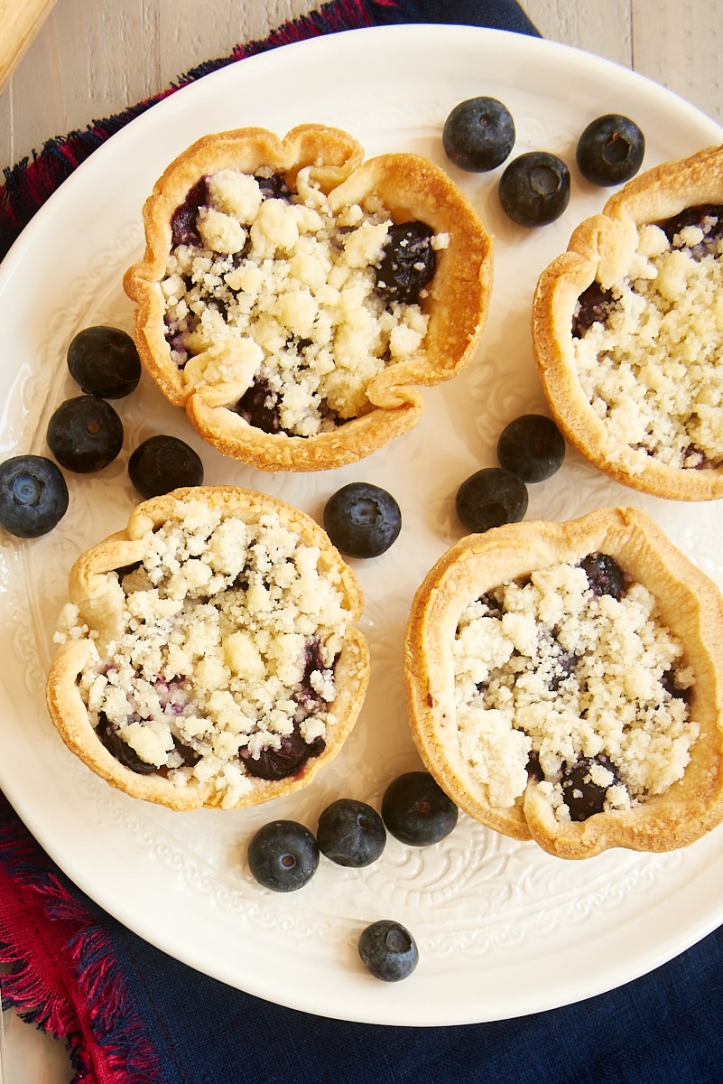 Overhead view of mini blueberry cream cheese pies on plate.