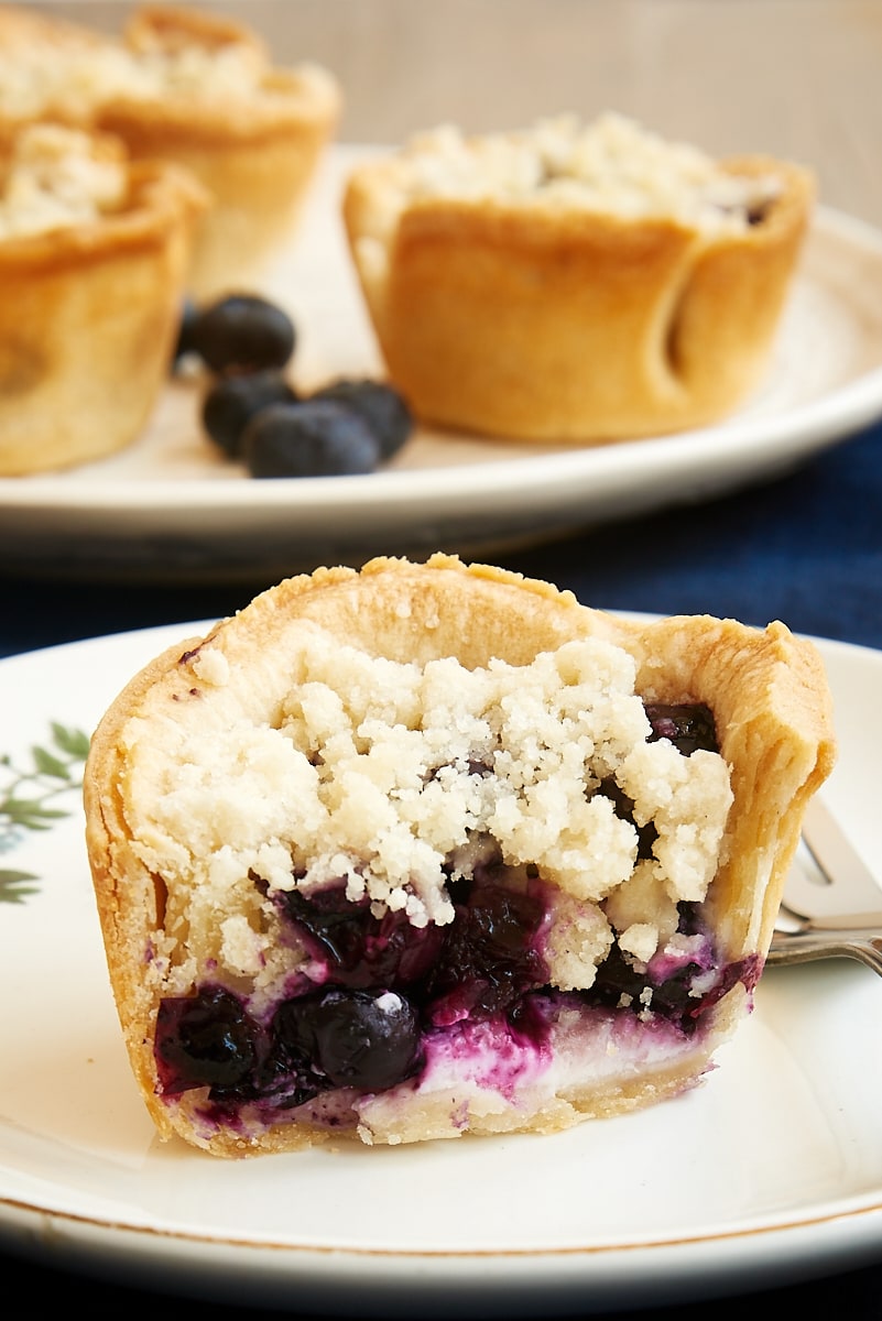 Mini blueberry cream cheese pie, cut in half on plate to show inside.