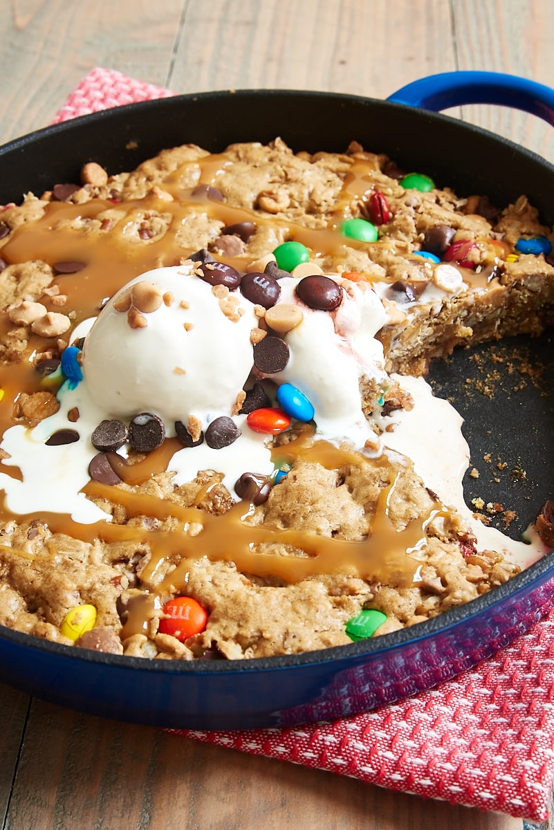Monster skillet cookie in cast iron skillet topped with ice cream, caramel and M&Ms