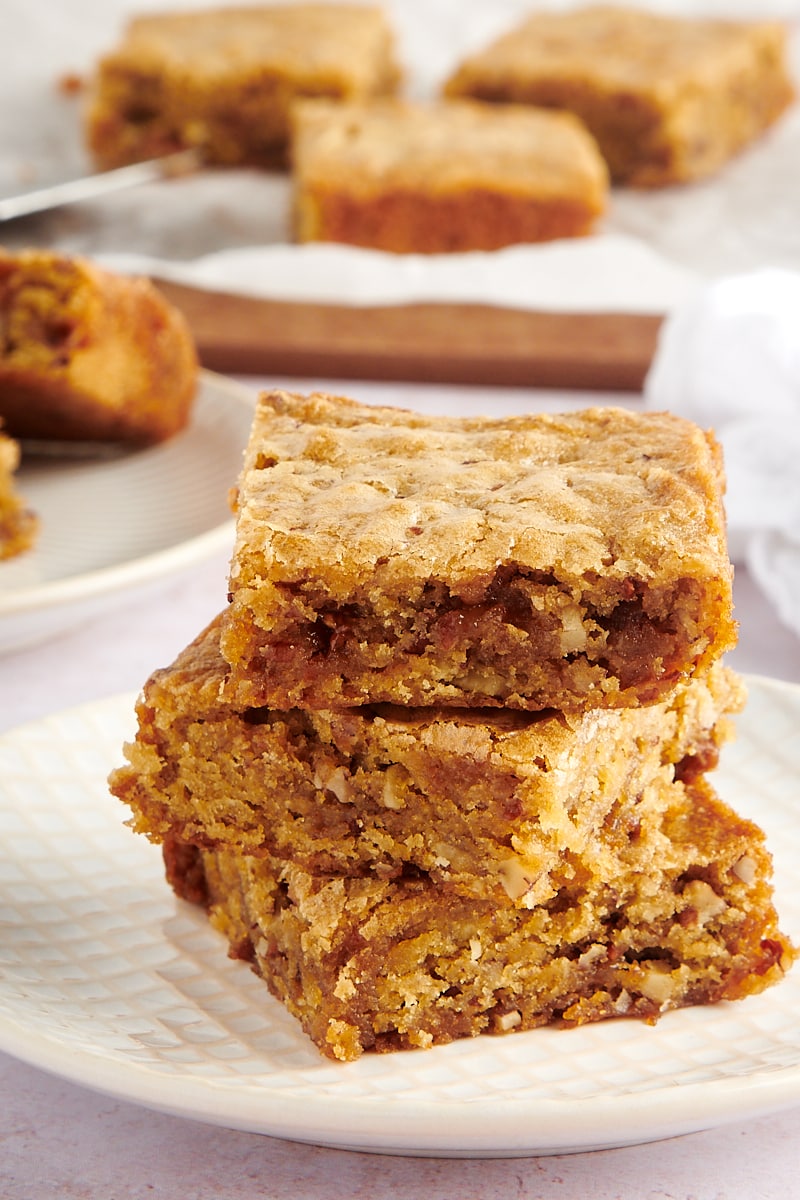 three blondies stacked on a white and beige plate