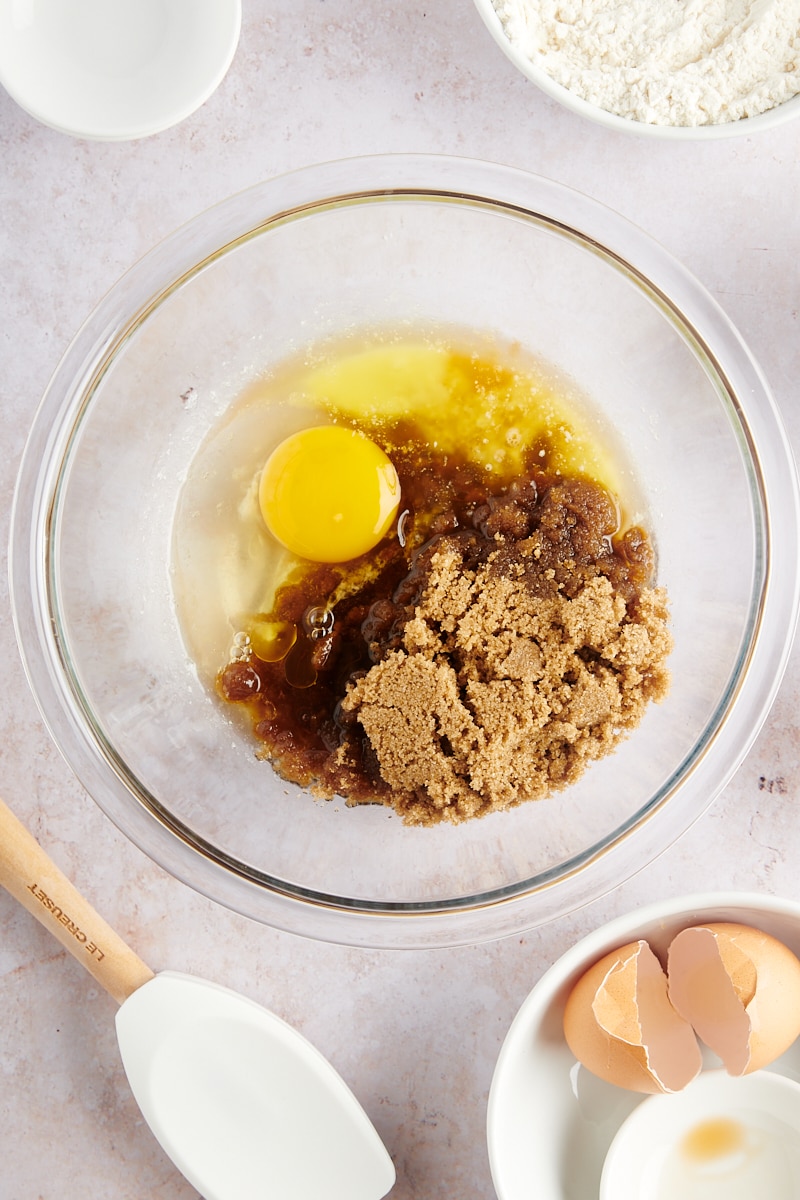 overhead view of butter, brown sugar, egg, and vanilla in a glass mixing bowl