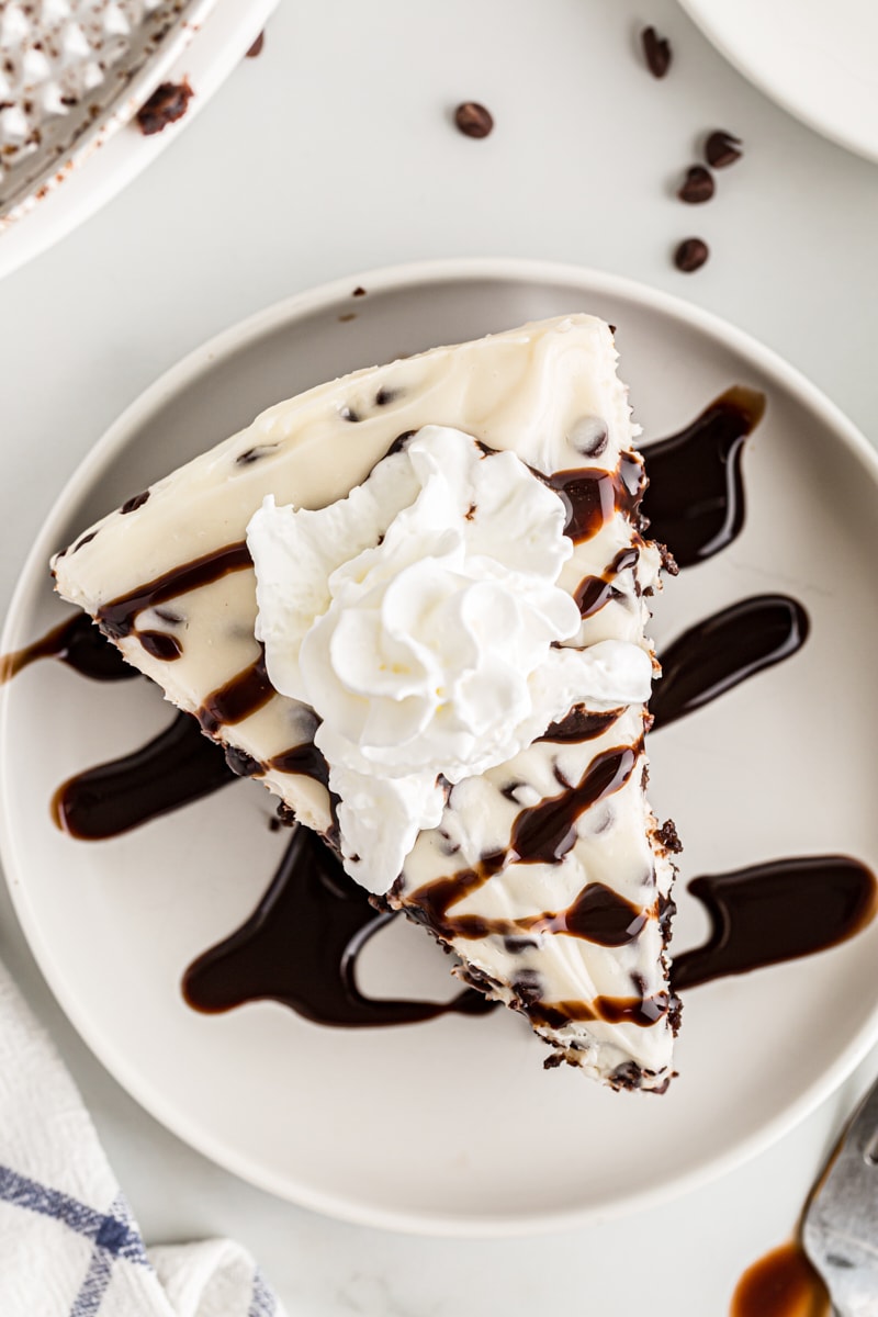 Slice of Chocolate Chip Cheesecake on plate with whipped cream and chocolate sauce