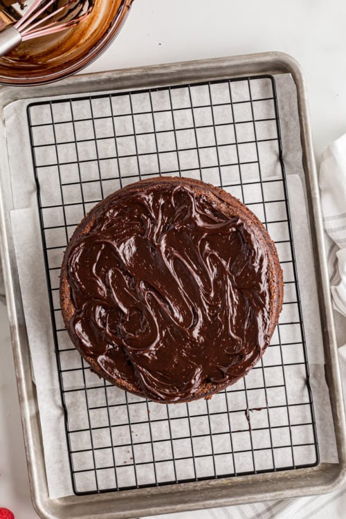 Frosted flourless chocolate cake on cooling rack