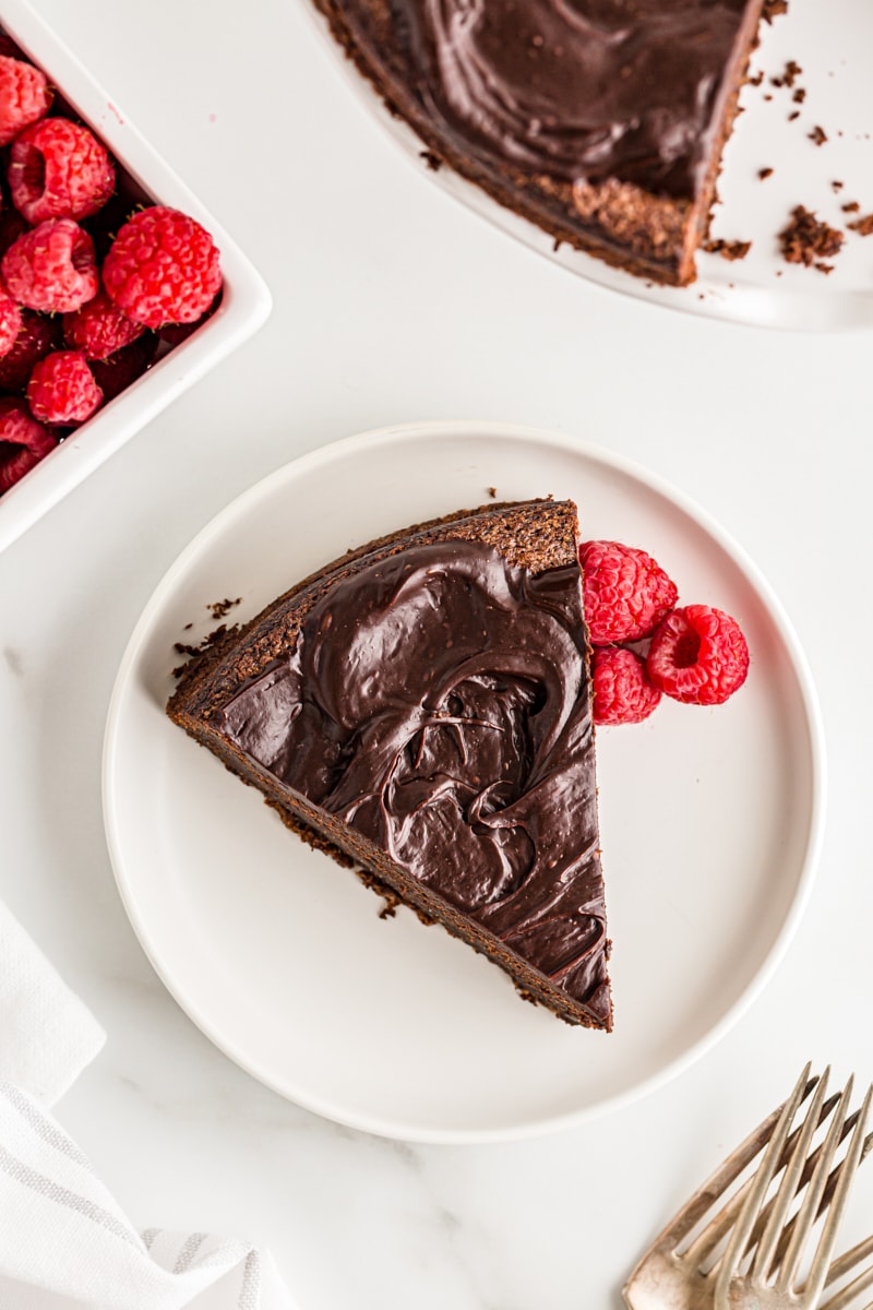 Overhead view of flourless chocolate cake on plate with raspberries