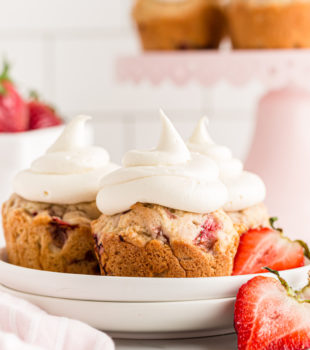 Three strawberry cupcakes on plate with fresh strawberries