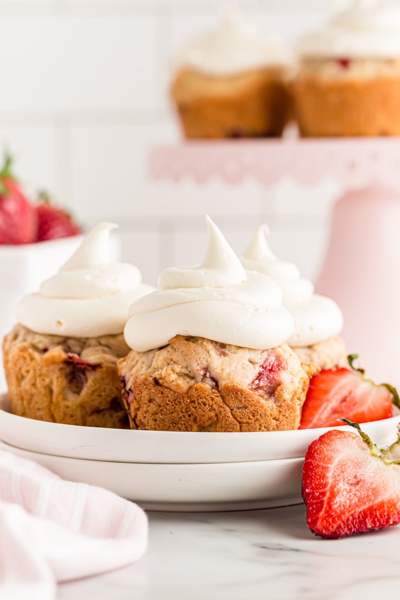 Three strawberry cupcakes on plate with fresh strawberries