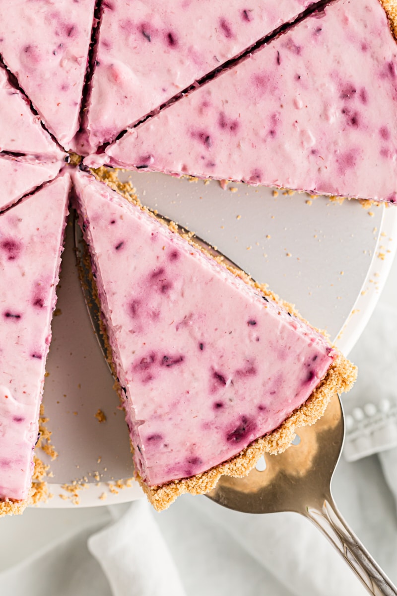 Overhead view of berry cheesecake slice being removed