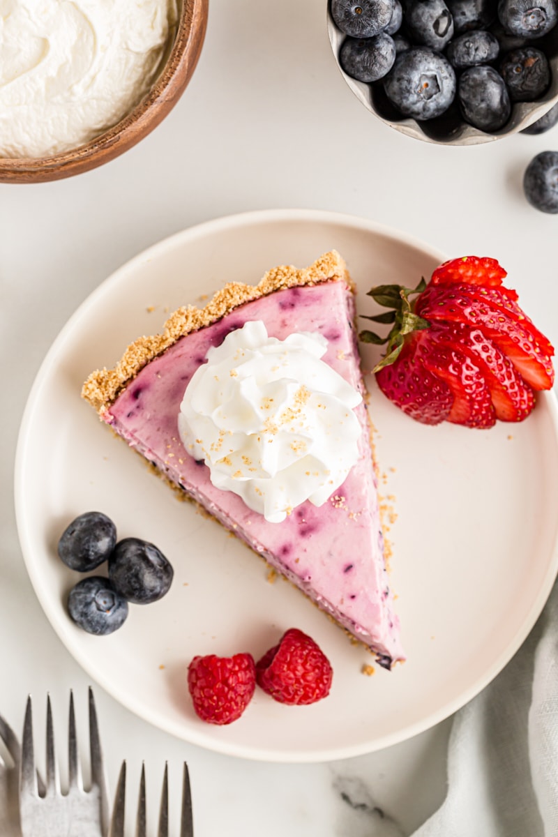 Overhead view of triple berry no-bake cheesecake on plate with fresh berries