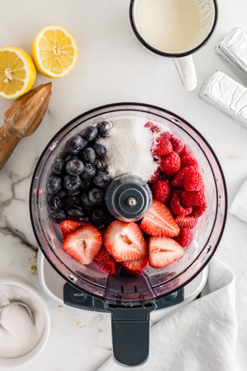 Overhead view of fresh berries and sugar in food processor