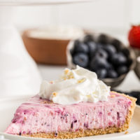 Slice of berry no-bake cheesecake on white plate