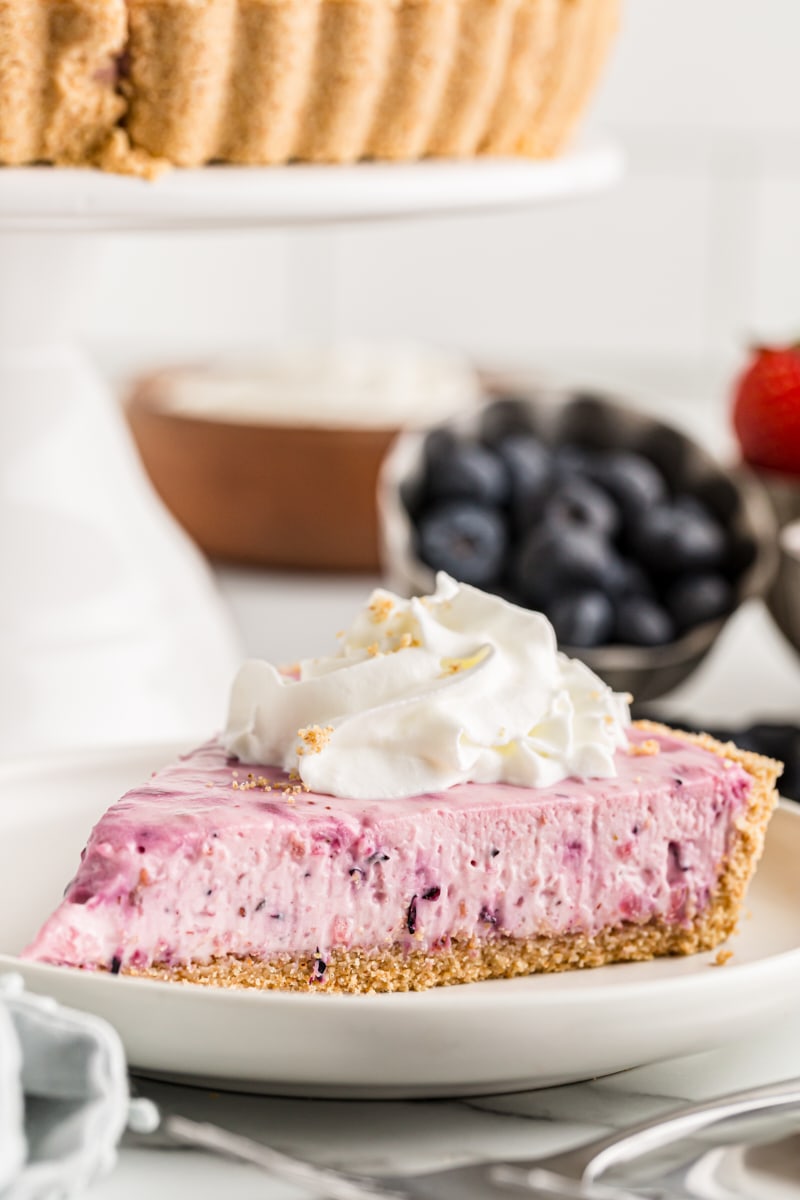 Slice of berry no-bake cheesecake on white plate