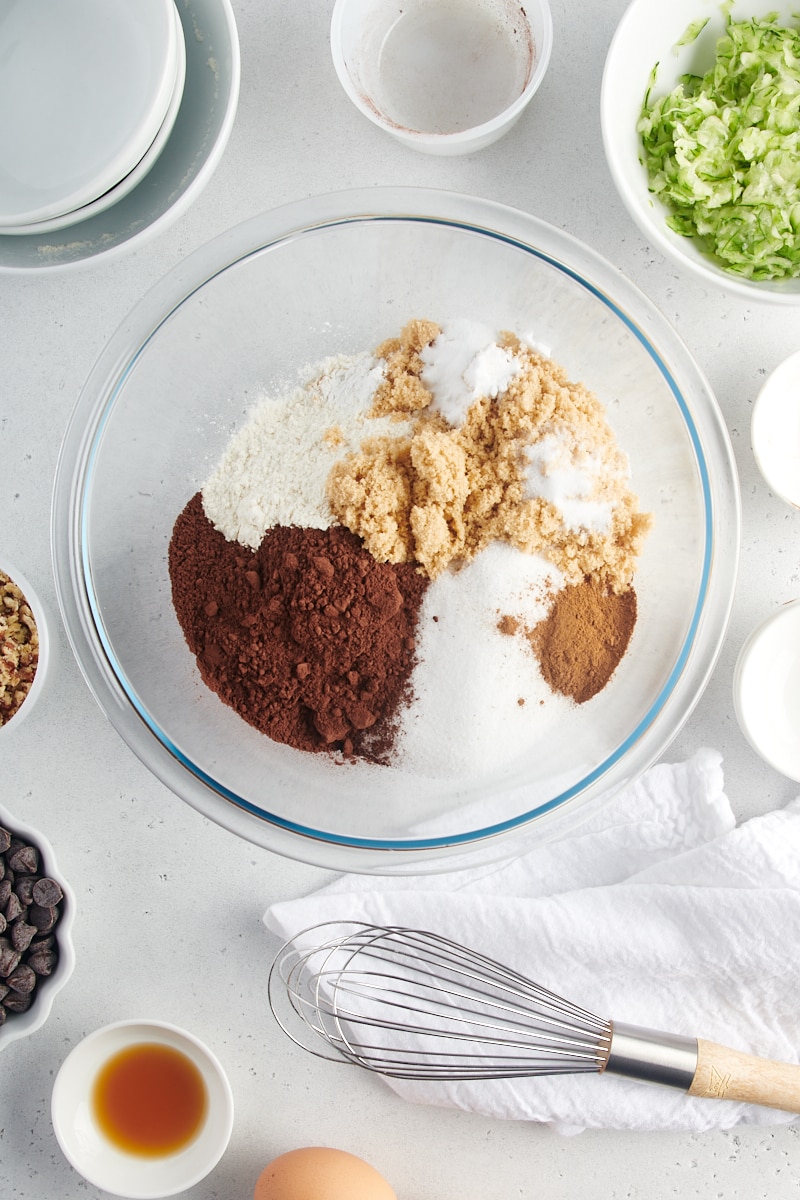 overhead view of flour, sugars, cocoa powder, baking powder, baking soda, cinnamon, and sugar in a glass mixing bowl