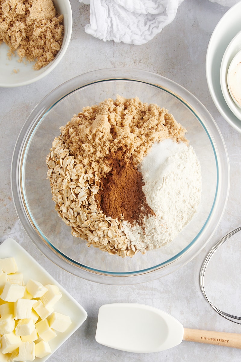 overhead view of oats, brown sugar, flour, cinnamon, and salt in a glass mixing bowl