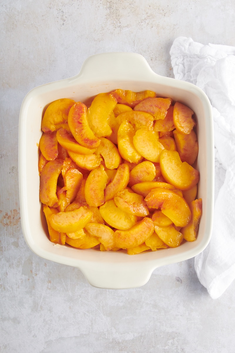 sliced peaches in a white baking dish